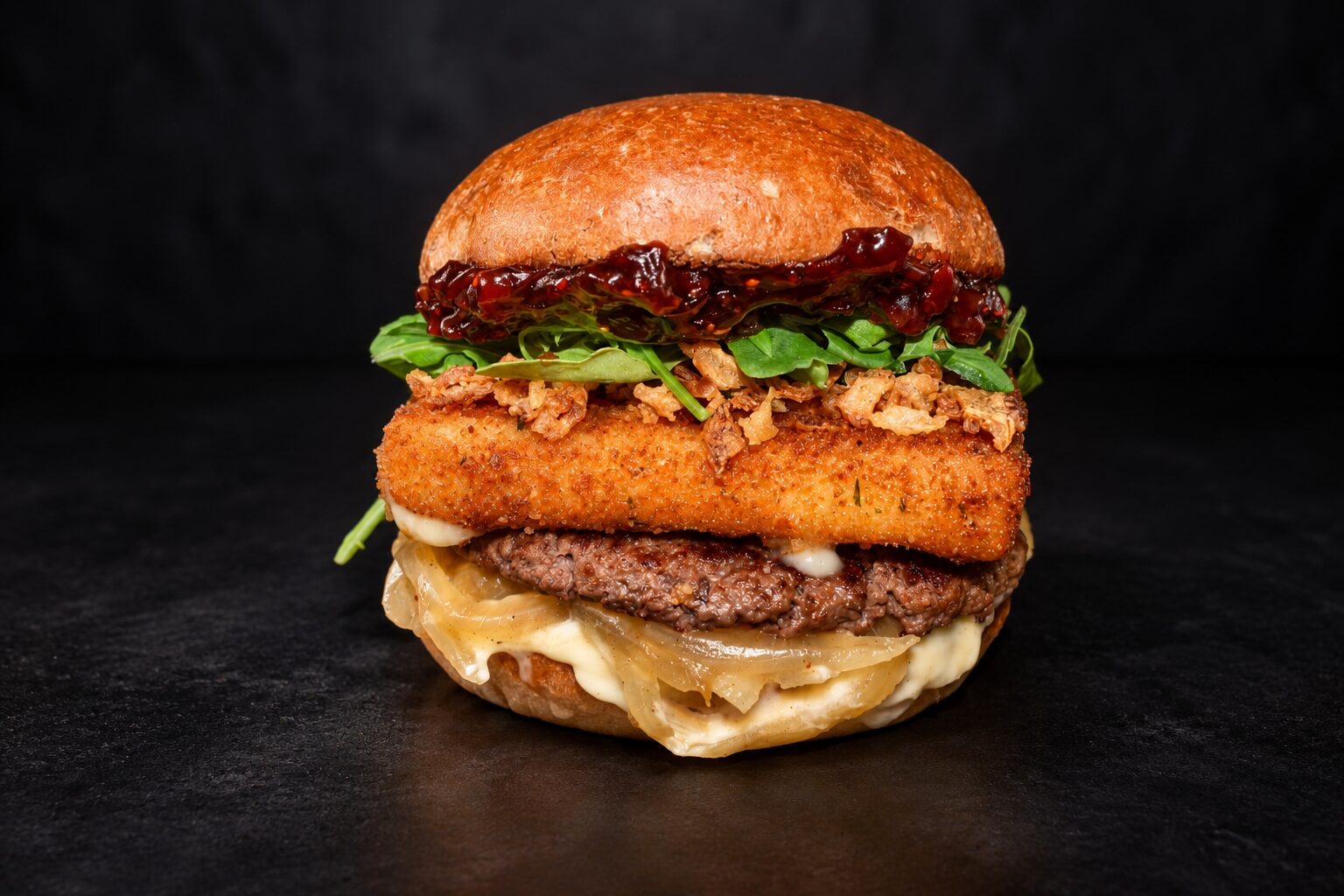 The Raspberry Bacon Crunch: raspberry bacon jam, arugula and crispy onions over a hand-breaded havarti patty and a beef patty on a toasted brioche bun